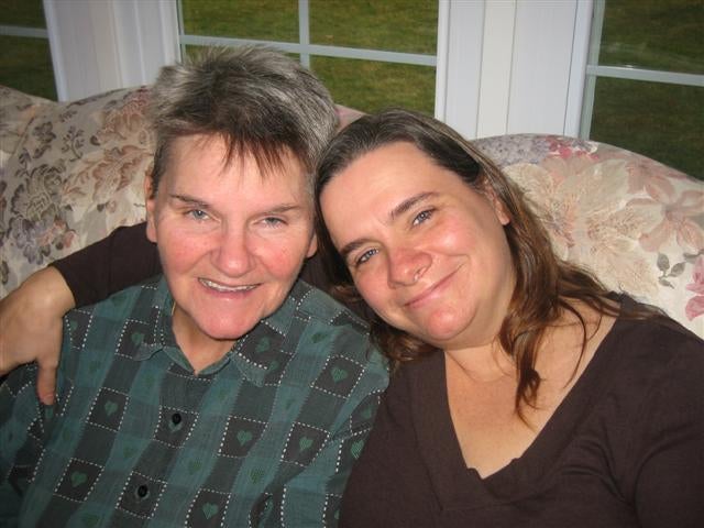 Joyce and Vicki Speegle seated on a couch with Vicki's arm around Joyce